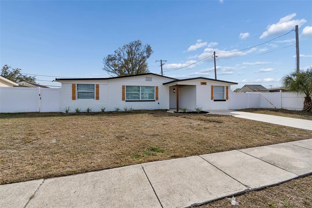 A single-story white house with a flat roof, brown shutters, and a white vinyl fence — 7910 W POWHATAN AVENUE, TAMPA, FL