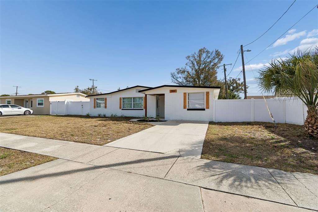 A single-story house with a white exterior, a concrete driveway, and a white vinyl fence — 7910 W POWHATAN AVENUE, TAMPA, FL