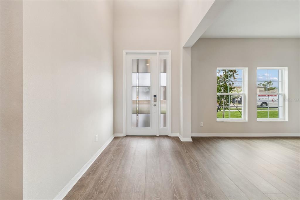 An entryway with light wood-look flooring, a white front door, and two windows — 7849 PAINTED SKY PLACE, LAND O LAKES, FL