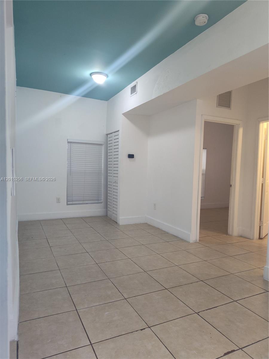 A room with beige tile flooring, white walls, and a blue-painted vaulted ceiling — 8028 NW 5th Ct Rear, Miami FL 33150, MIAMI, FL