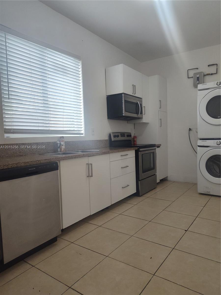 A kitchen features white cabinets, stainless steel appliances, a window with blinds, and a washer-dryer — 8028 NW 5th Ct Rear, Miami FL 33150, MIAMI, FL