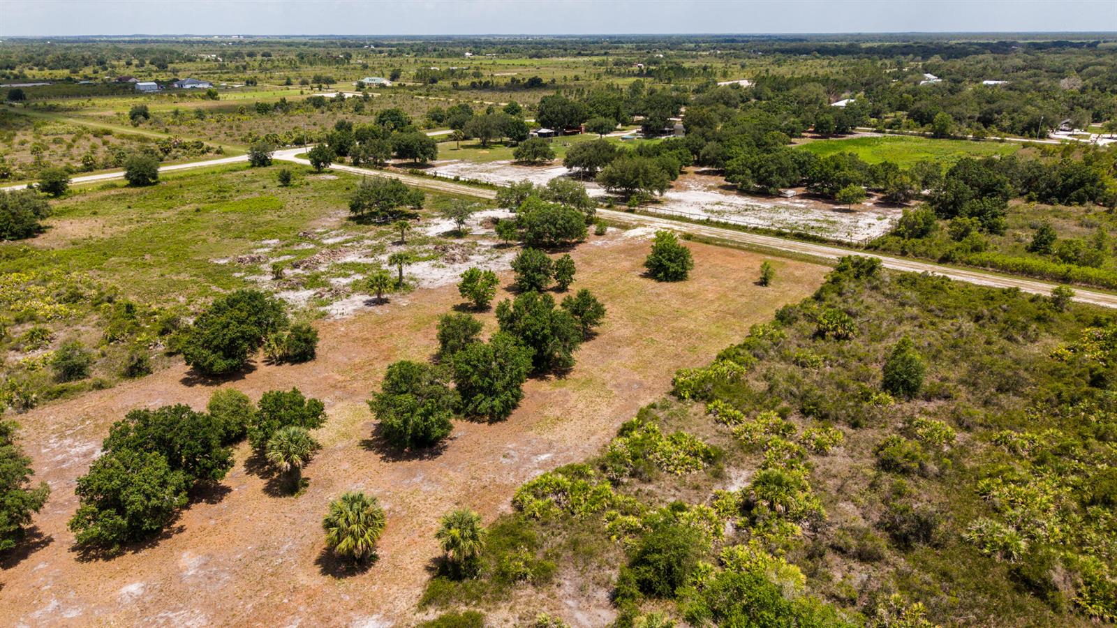 An aerial view shows a large, grassy, partially wooded plot of land with dirt roads — 19371 NW 254th Street, Okeechobee FL 34972, OKEECHOBEE, FL
