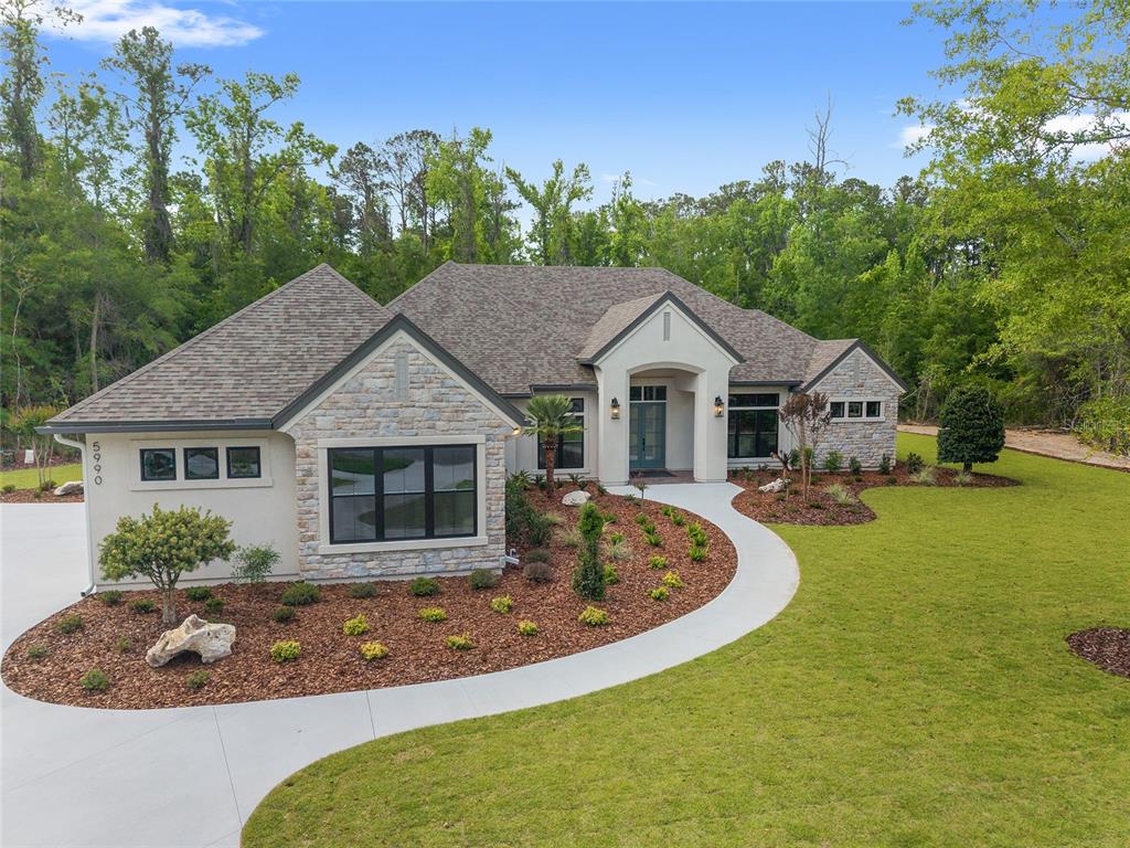 A single-story house with a stone and stucco exterior features a curved concrete walkway — 5990 NW 88TH WAY, GAINESVILLE, FL