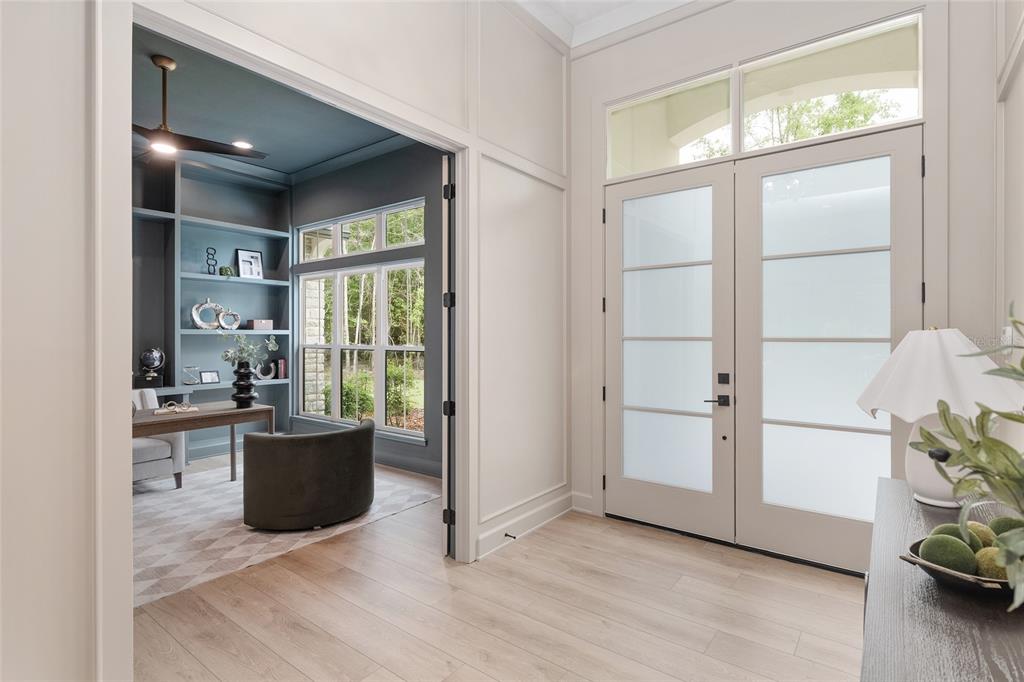 An entryway with light wood floors leads to a blue-walled home office with built-in shelves — 5990 NW 88TH WAY, GAINESVILLE, FL