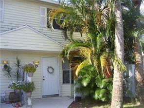 A two-story townhouse exterior with light siding, a white front door, and lush palm trees — 2843 NE 15th Street, Pompano Beach FL 33062, POMPANO BEACH, FL