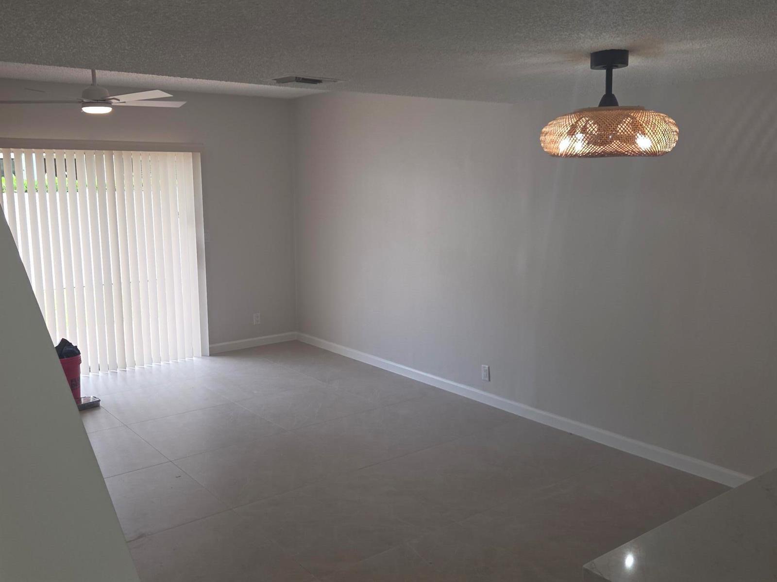 An empty living room with light tile floors, a ceiling fan, and a woven pendant light — 2843 NE 15th Street, Pompano Beach FL 33062, POMPANO BEACH, FL