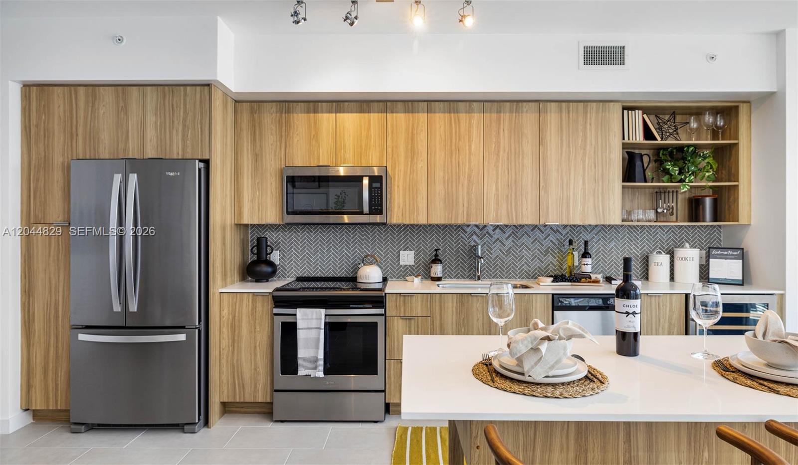 A modern kitchen features light wood cabinetry, stainless steel appliances, and a gray herringbone backsplash — 2150 N Bayshore Dr # 1602, Miami FL 33137, MIAMI, FL