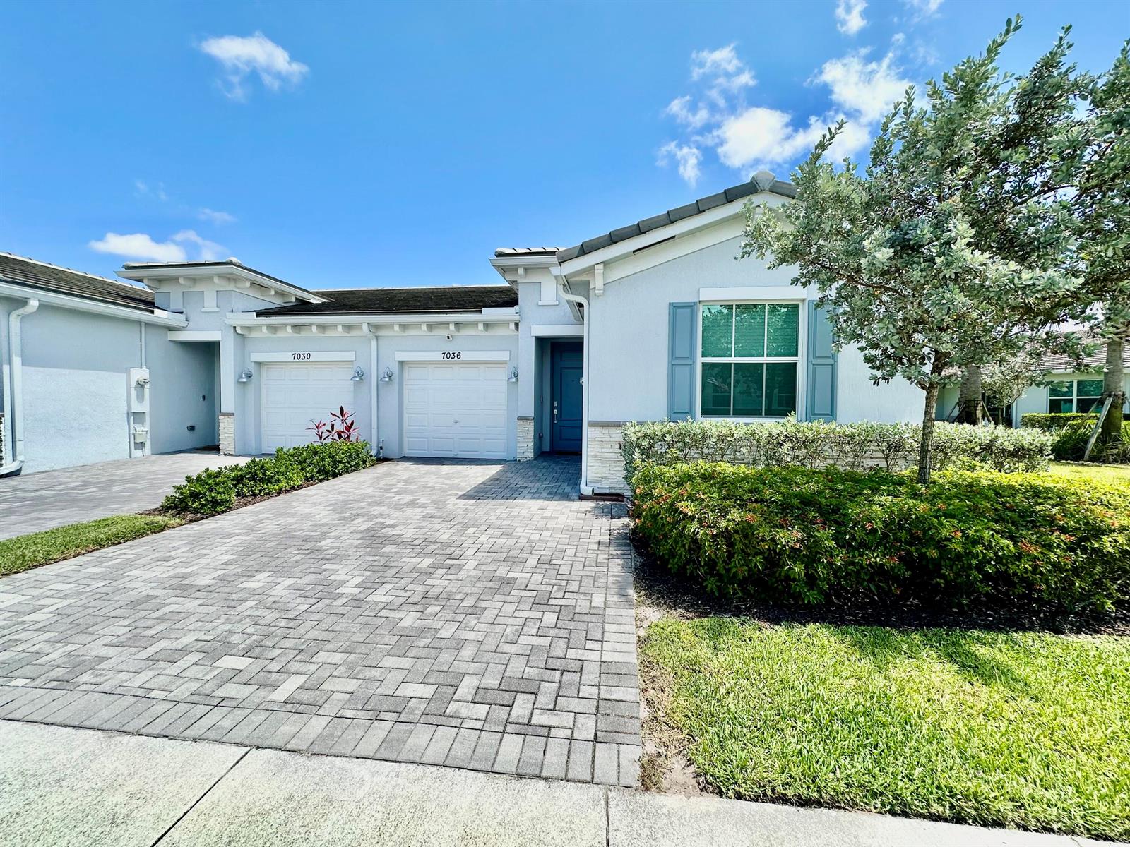 A light-colored single-story house with a paver driveway, two garage doors, and a front garden — 7036 Peters Lane, Delray Beach FL 33446, DELRAY BEACH, FL