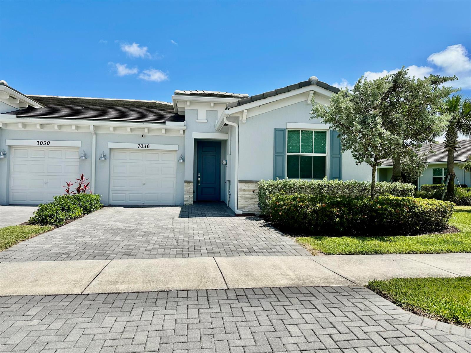 A light-colored single-story house with a paved driveway, two garage doors, and blue shutters — 7036 Peters Lane, Delray Beach FL 33446, DELRAY BEACH, FL