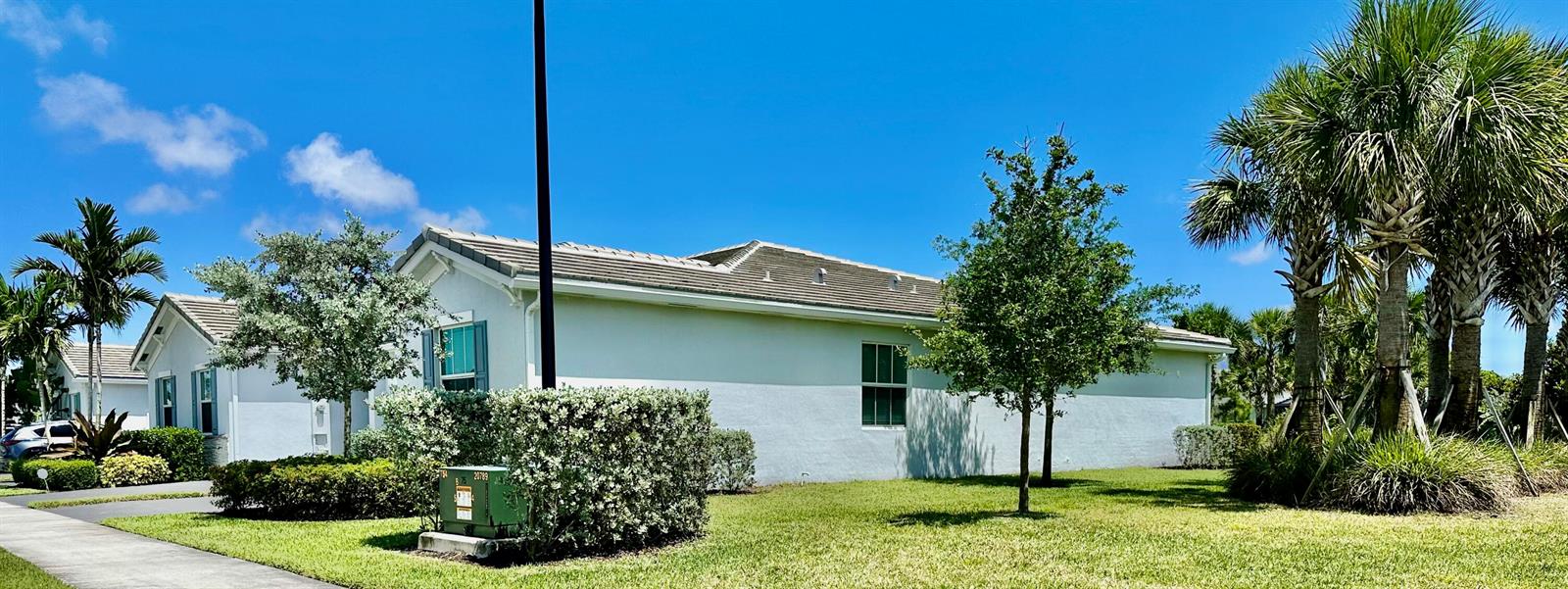 A side view of a light-colored residential house with a lawn, palm trees, and landscaping — 7036 Peters Lane, Delray Beach FL 33446, DELRAY BEACH, FL