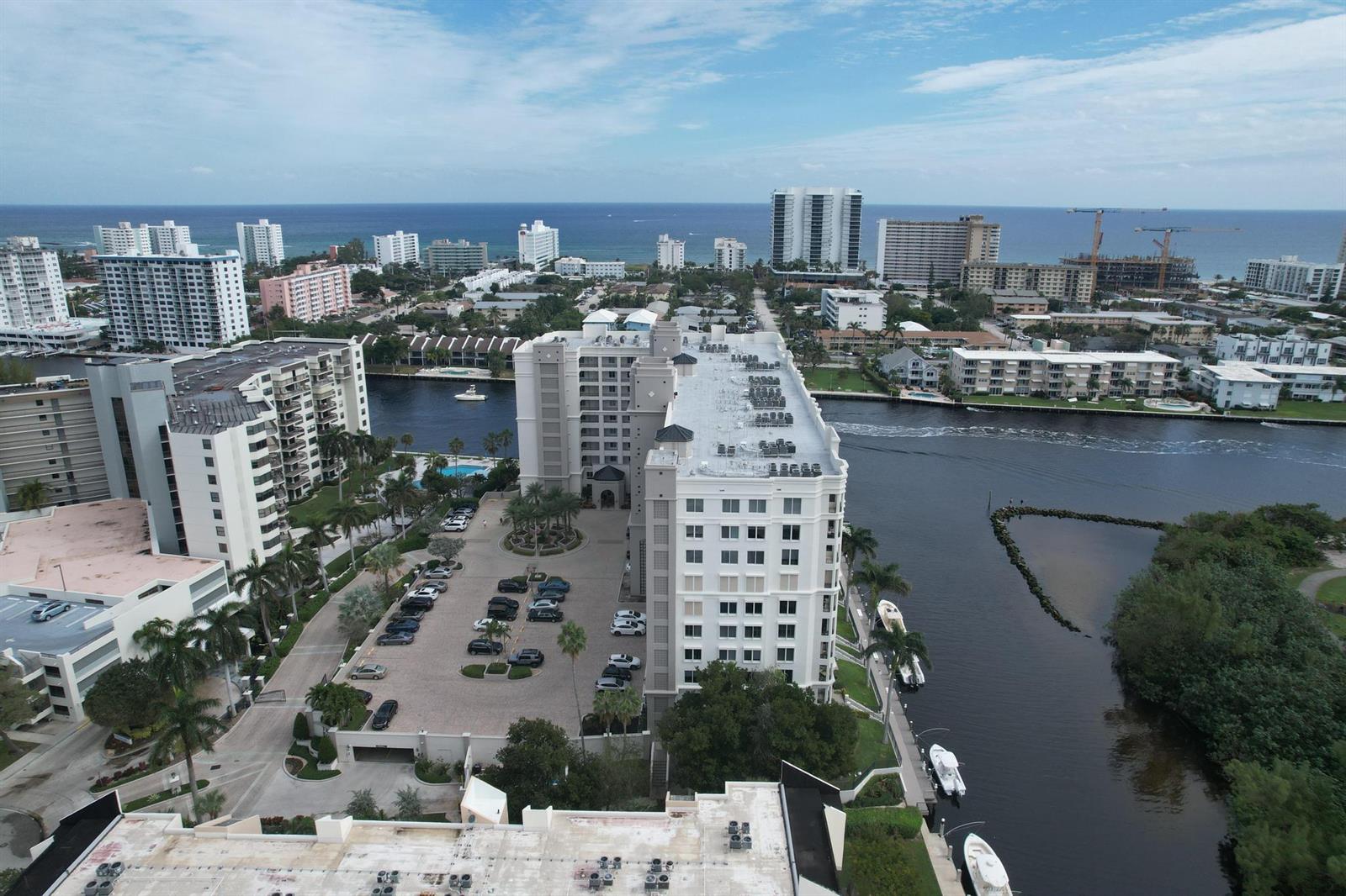 An aerial view shows a multi-story apartment building with a parking lot and waterfront access — 2880 NE 14th St Causeway # 904, Pompano Beach FL 33062, POMPANO BEACH, FL