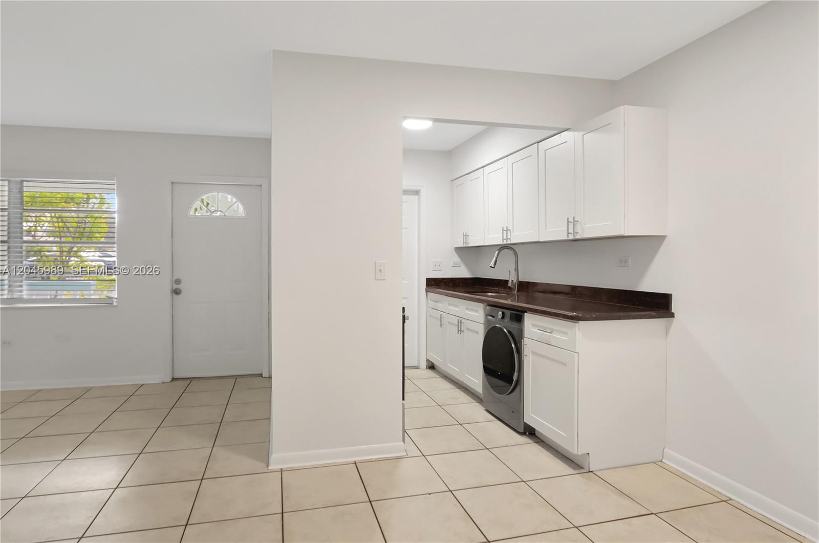 A kitchen area features white cabinets, dark countertops, and a built-in front-load washing machine — 202 N K St # 7, Lake Worth FL 33460, LAKE WORTH, FL