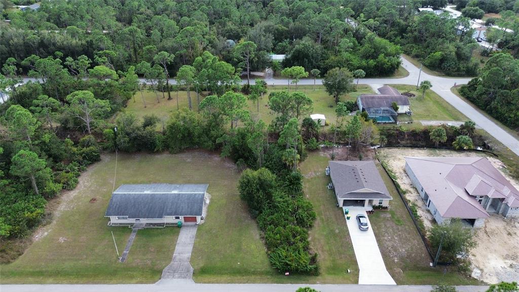 An aerial view shows two houses on large, grassy lots surrounded by dense trees — 27301 CHINQUAPIN DRIVE, PUNTA GORDA, FL