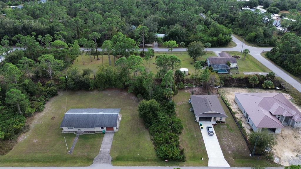 An aerial view shows two houses with driveways and lawns surrounded by dense trees — 27301 CHINQUAPIN DRIVE, PUNTA GORDA, FL