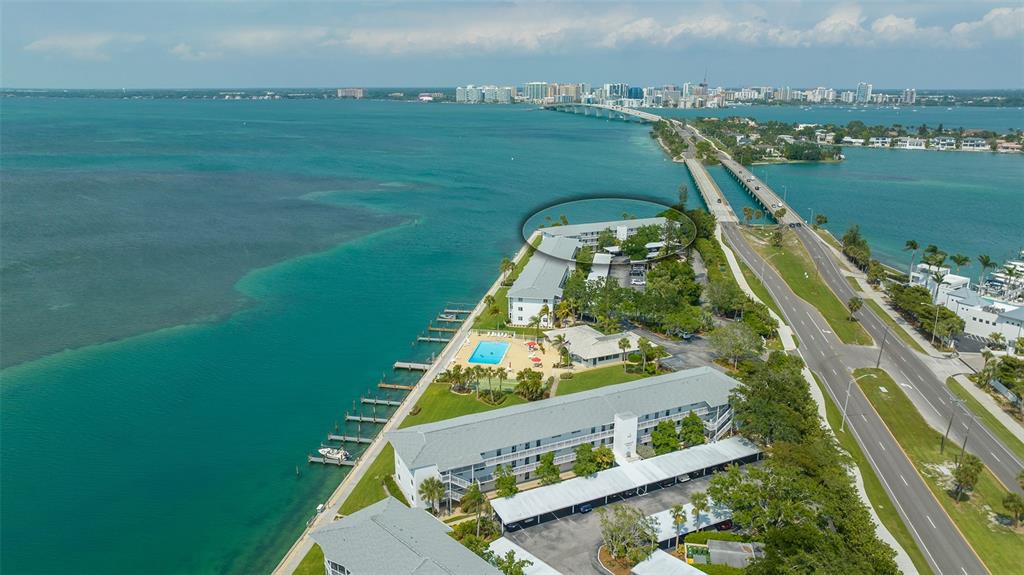 An aerial view of a waterfront apartment complex with a pool, docks, and a bridge — 777 JOHN RINGLING BOULEVARD UNIT 32, SARASOTA, FL