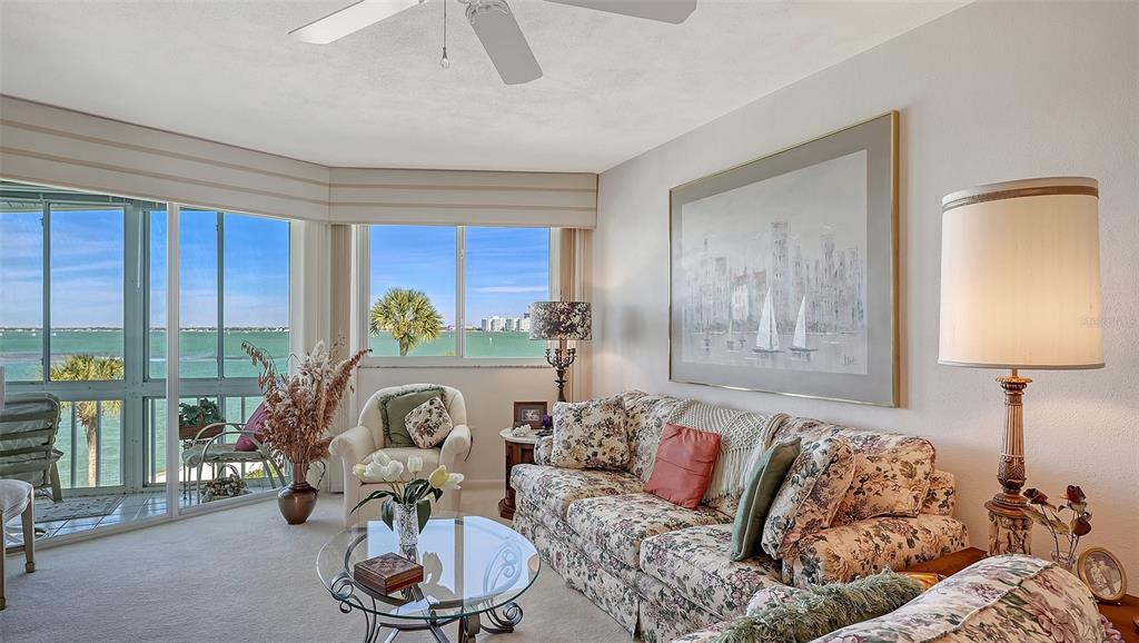 A living room features a floral sofa, a glass coffee table, and large windows overlooking water — 777 JOHN RINGLING BOULEVARD UNIT 32, SARASOTA, FL