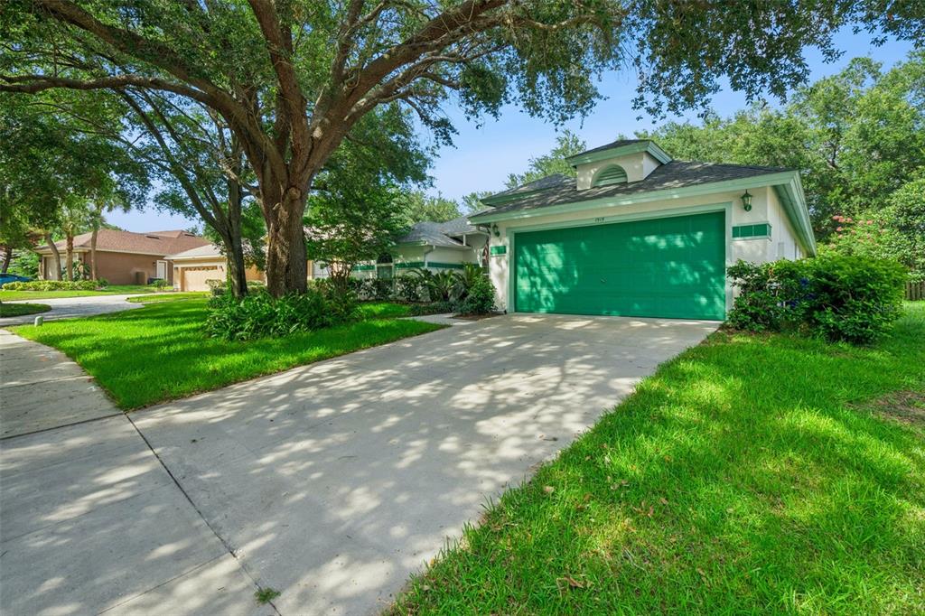 A single-story house with a green garage door and a large tree in the yard — 1515 ACROPOLIS CIRCLE, OCOEE, FL