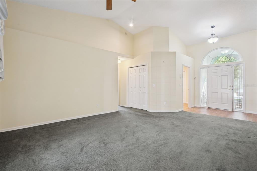 A living room features gray carpeting, vaulted ceilings, a ceiling fan, and a front entryway — 1515 ACROPOLIS CIRCLE, OCOEE, FL