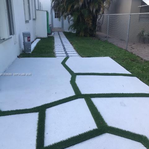A backyard patio features large concrete pavers separated by strips of artificial turf — 3244 SW 3rd St # L, Miami FL 33135, MIAMI, FL