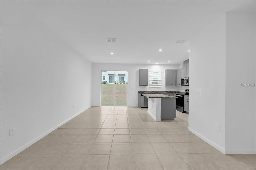 An open-concept kitchen and living area with tile flooring and gray cabinetry — 1186 SEASIDE MIST TRAIL, KISSIMMEE, FL