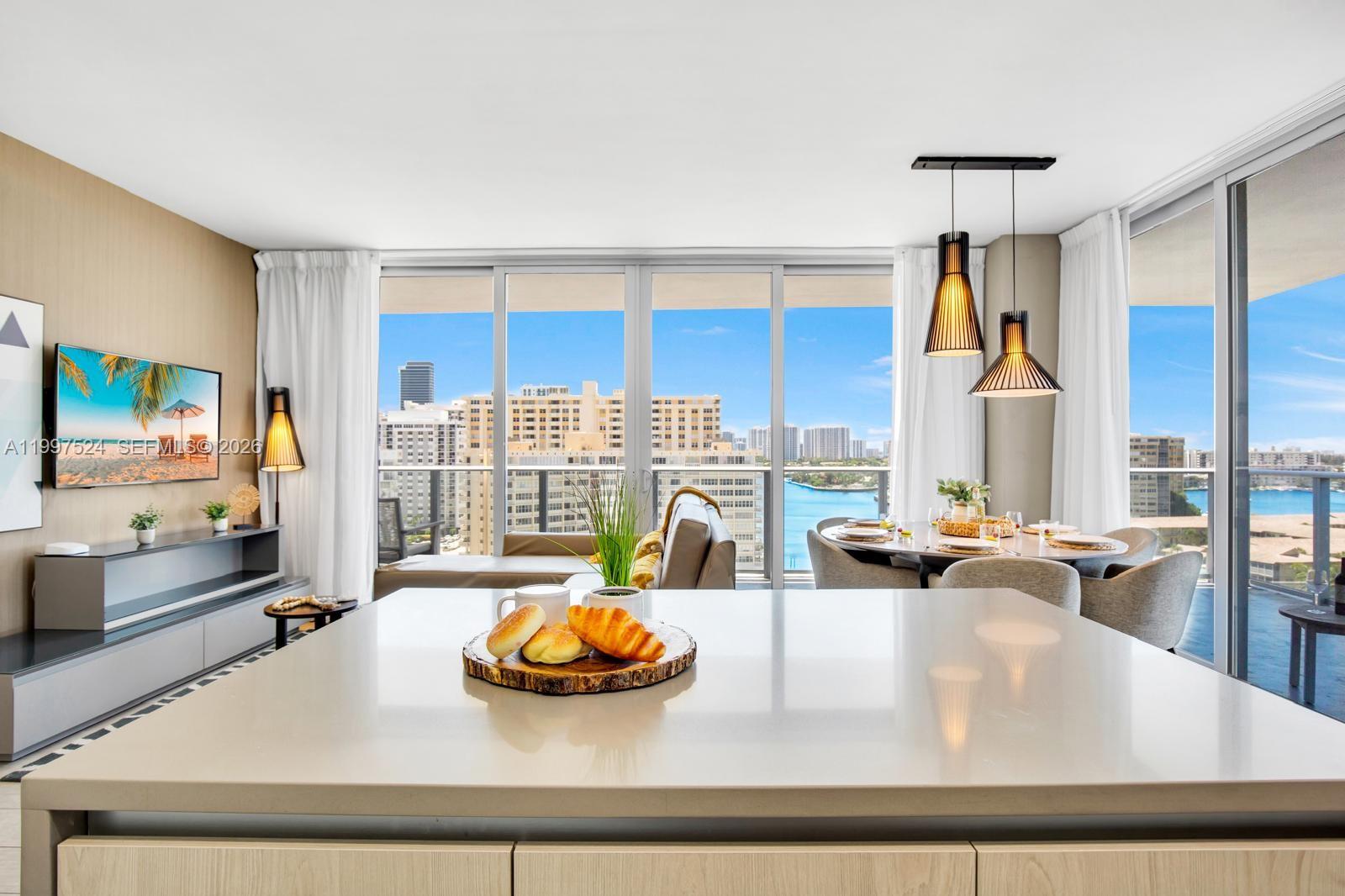 A bright, open-concept living and dining area features a kitchen island with a water view — 4010 S Ocean Dr # R708, Hollywood FL 33019, HOLLYWOOD, FL