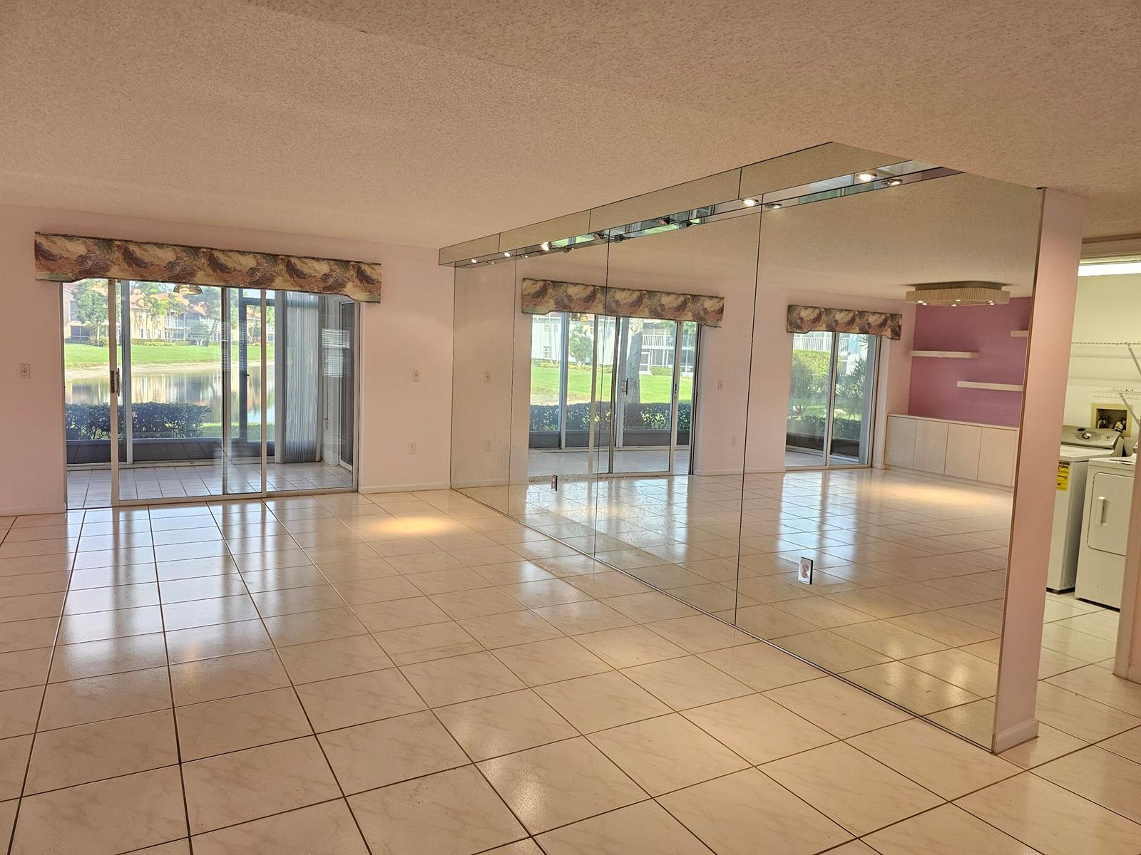 A living room with light tile flooring, a mirrored wall, and sliding glass doors to outdoors — 9963 Seacrest Circle # 101, Boynton Beach FL 33437, BOYNTON BEACH, FL