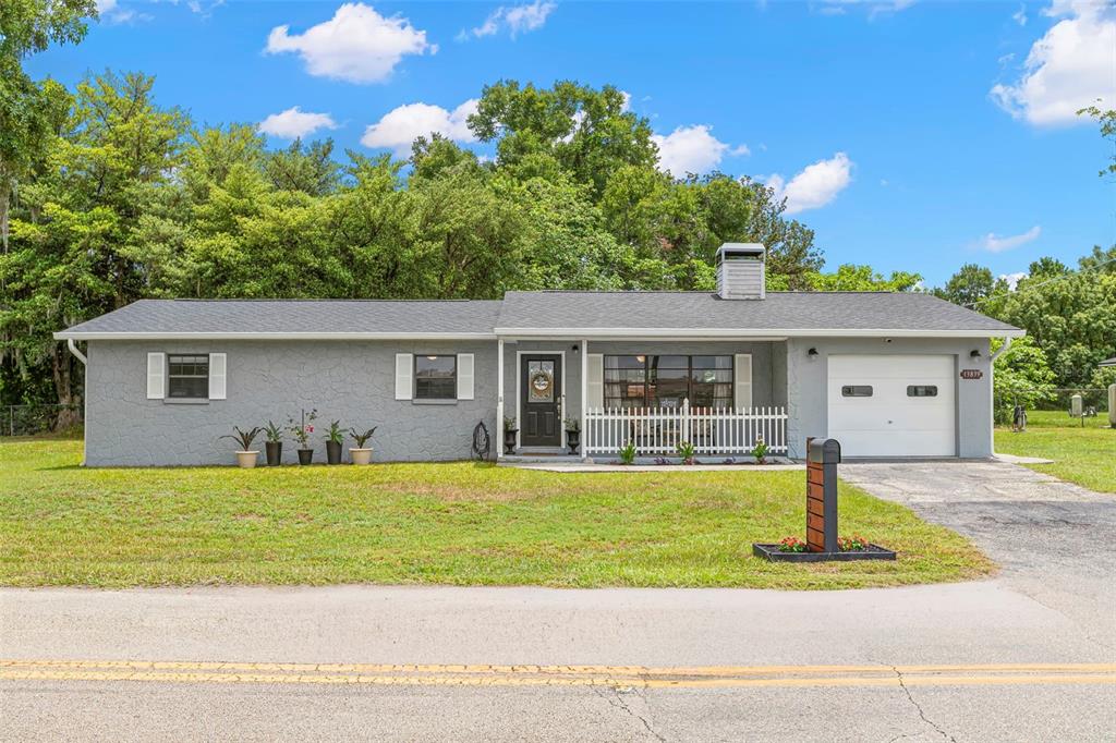 A single-story gray house with a white picket fence, a garage, and a chimney — 13839 GLEN HARWELL ROAD, DOVER, FL