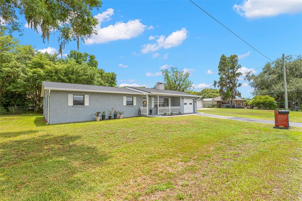 A single-story gray house with a white-railed porch sits on a large grassy lot — 13839 GLEN HARWELL ROAD, DOVER, FL