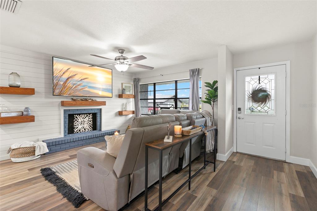 A living room features a fireplace with a shiplap wall, a sofa, and an entryway door — 13839 GLEN HARWELL ROAD, DOVER, FL