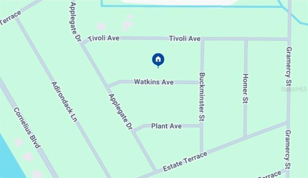 A paved road runs alongside a wooded, undeveloped lot with a blue marker sign — 15180 WATKINS AVENUE, PORT CHARLOTTE, FL