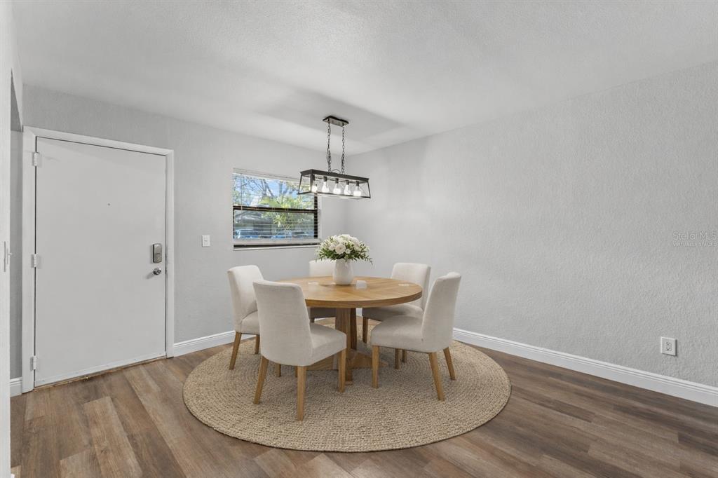 A living room and dining area with light wood floors, a sofa, and a ceiling fan — 3034 EASTLAND BOULEVARD UNIT D104, CLEARWATER, FL