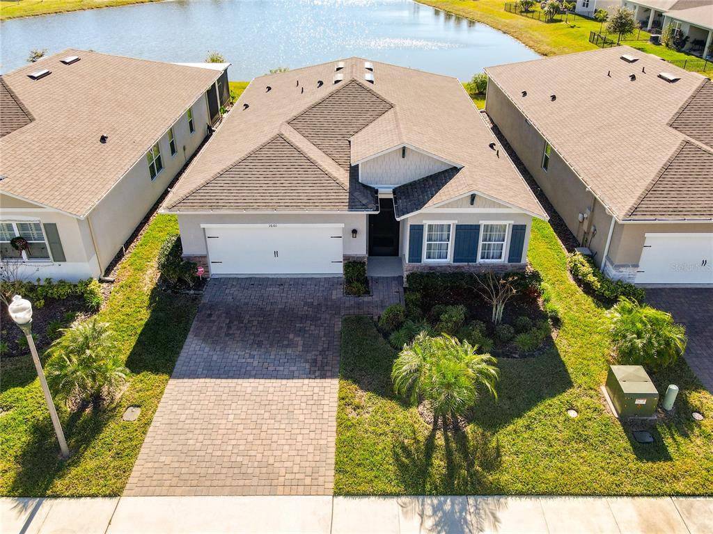 An aerial view shows a single-story suburban house with a paved driveway and a pond — 1601 DELPHI WAY, NEW SMYRNA BEACH, FL