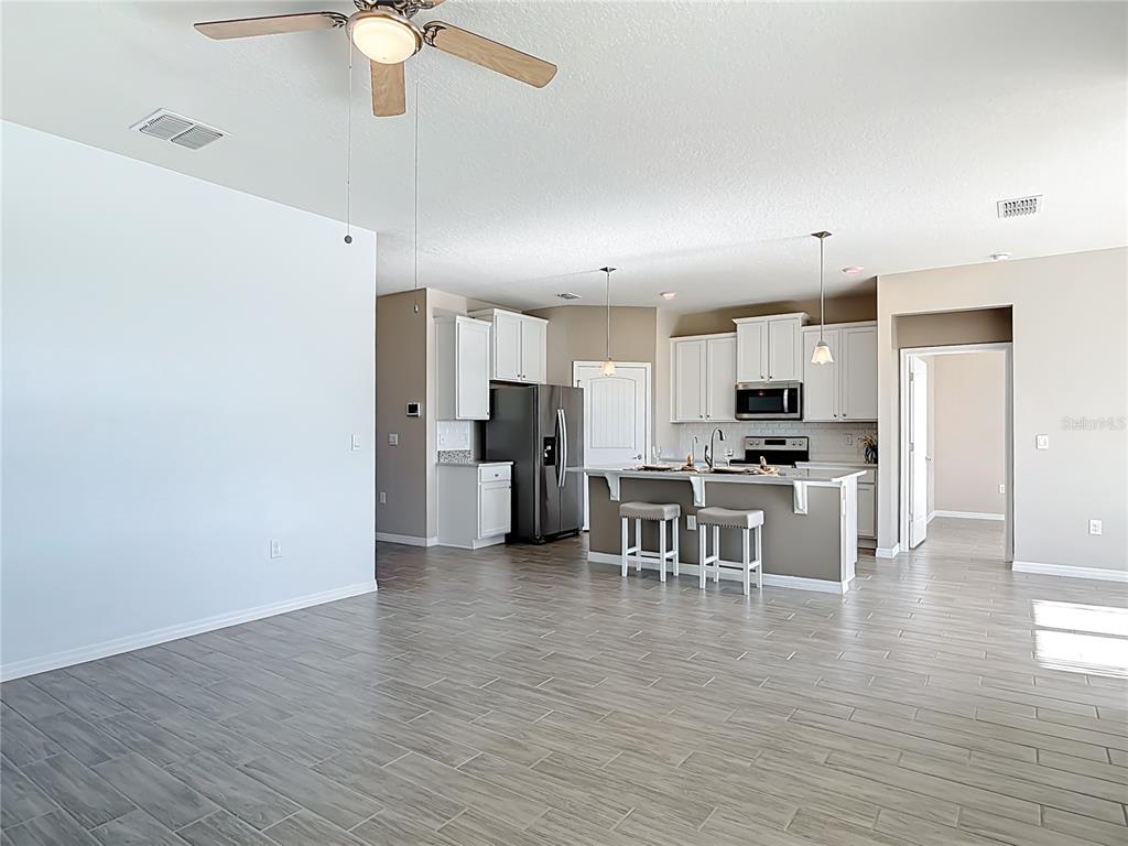 An open-concept kitchen with white cabinets, a center island, and gray wood-look tile flooring — 1601 DELPHI WAY, NEW SMYRNA BEACH, FL