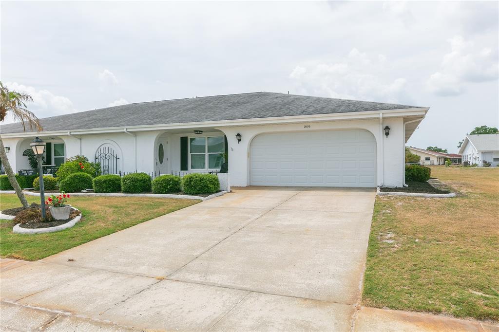 A white, single-story house with a two-car garage and a concrete driveway — 1616 BENTWOOD DRIVE, SUN CITY CENTER, FL