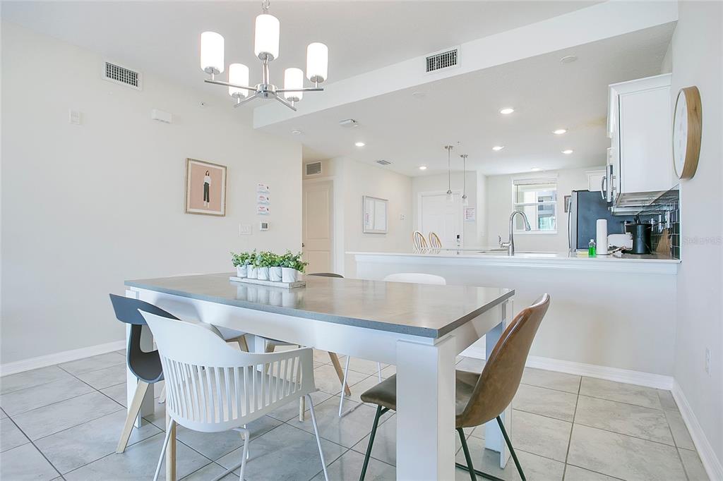A dining area with a gray table and mixed chairs sits before an open kitchen — 3120 PARADOX CIRCLE UNIT 204, KISSIMMEE, FL