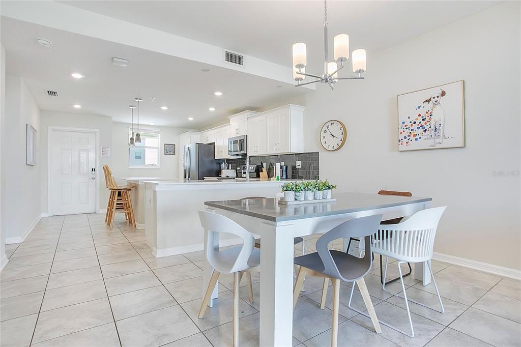 A dining area with a modern table and chairs sits adjacent to an open-concept kitchen — 3120 PARADOX CIRCLE UNIT 204, KISSIMMEE, FL