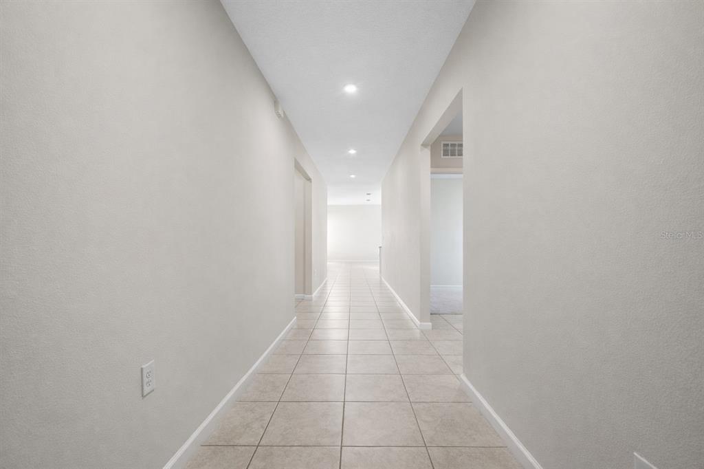 A long, tiled hallway with light-colored walls leads toward an open living area — 1125 CATSKILL DRIVE, HAINES CITY, FL