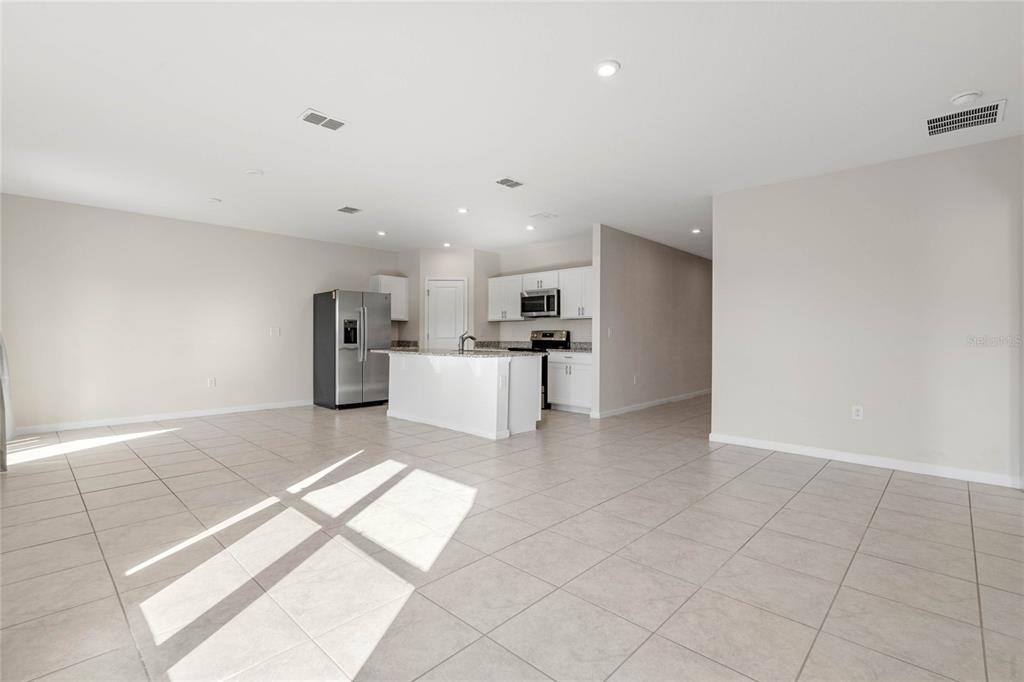 An open-concept kitchen features white cabinetry, a center island, and stainless steel appliances — 1125 CATSKILL DRIVE, HAINES CITY, FL