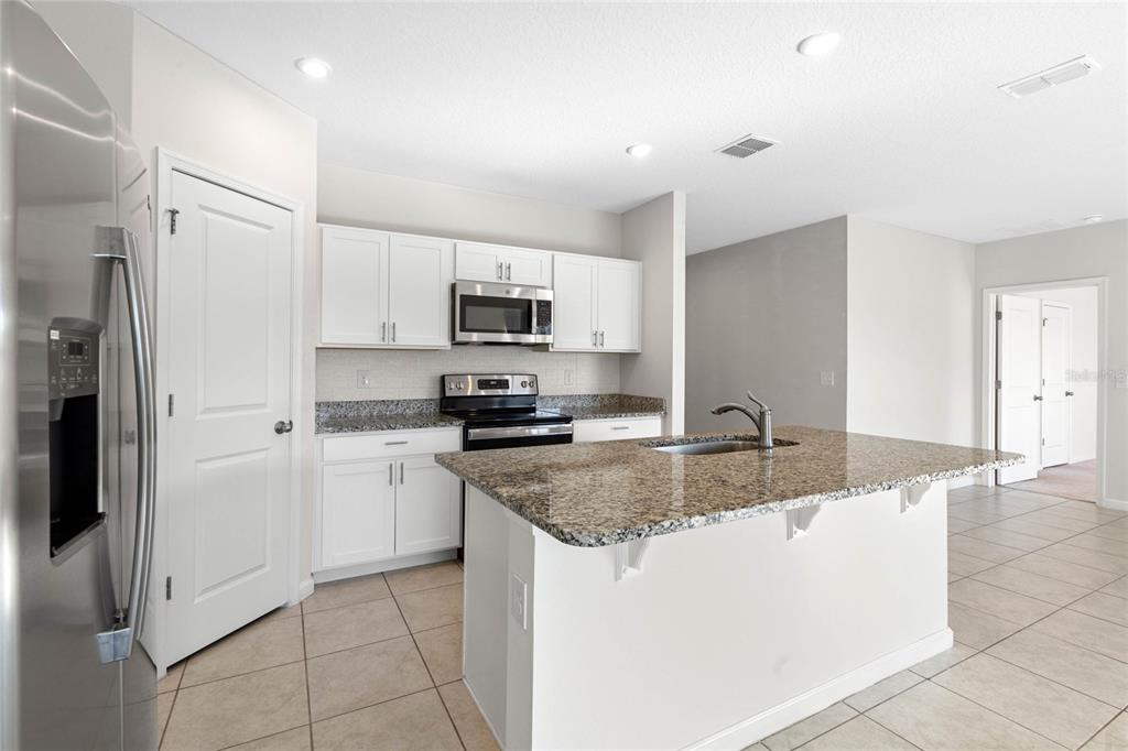 A kitchen with white cabinets, granite countertops, a center island, and stainless steel appliances — 1125 CATSKILL DRIVE, HAINES CITY, FL