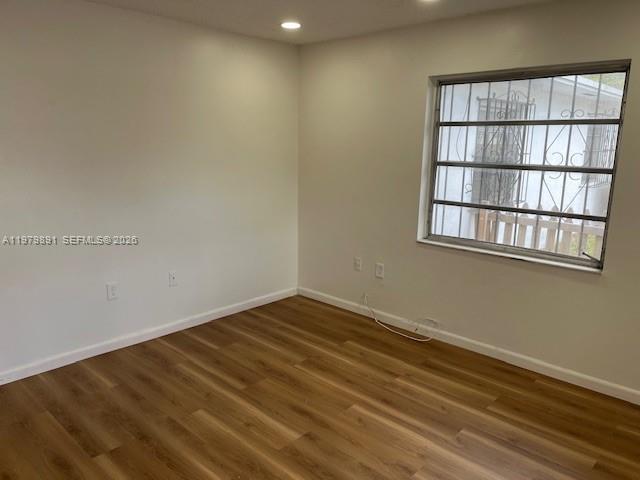 An empty room features wood-look flooring, white walls, recessed lighting, and a window with bars — 800 NW 29th Ter, Miami FL 33127, MIAMI, FL