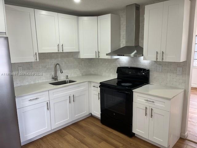 A kitchen features white shaker cabinets, light countertops, a black stove, and wood-look flooring — 800 NW 29th Ter, Miami FL 33127, MIAMI, FL
