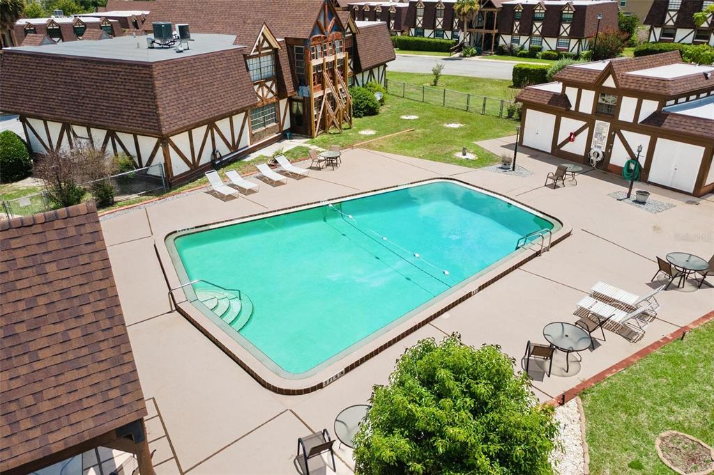 An aerial view of a rectangular swimming pool surrounded by a concrete deck and buildings — 500 NEWELL HILL ROAD UNIT 108D, LEESBURG, FL