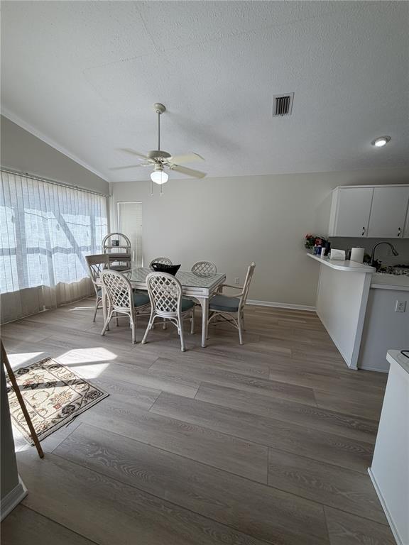 A dining area with a glass-top table, wicker chairs, and light wood-look flooring — 10542 MAGRATH LANE, NEW PORT RICHEY, FL