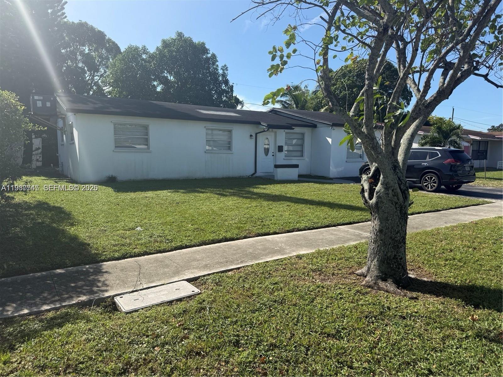 A single-story white house with a lawn, a sidewalk, and a tree in the foreground — 4910 NW 18th St, Lauderhill FL 33313, LAUDERHILL, FL