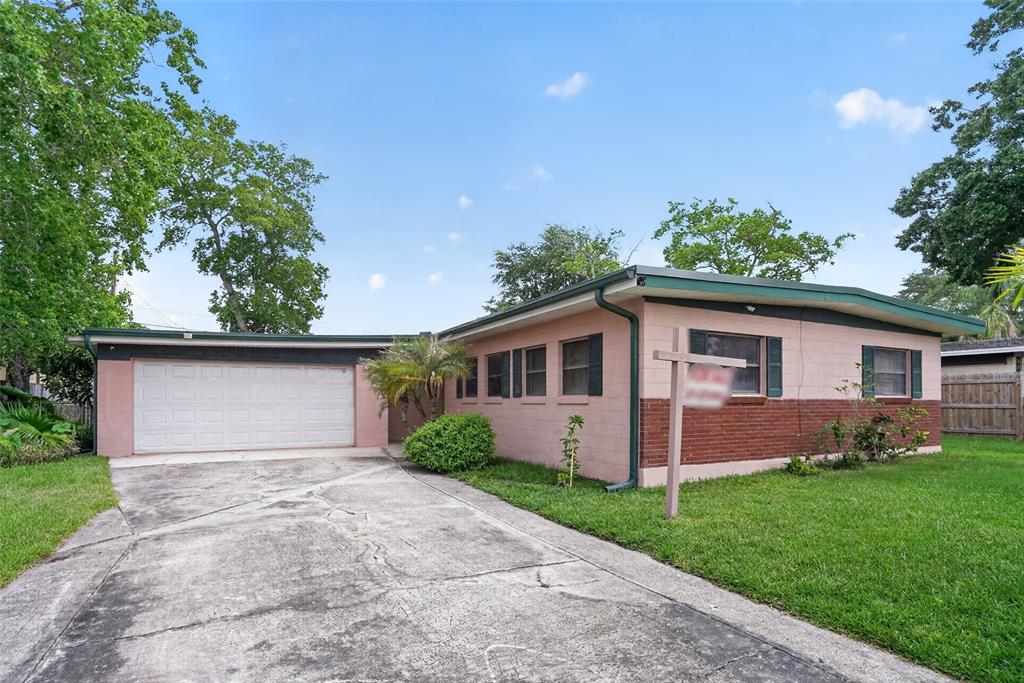 A single-story house with a pink and brick exterior, a garage, and a concrete driveway — 580 GARDENIA CIRCLE, TITUSVILLE, FL