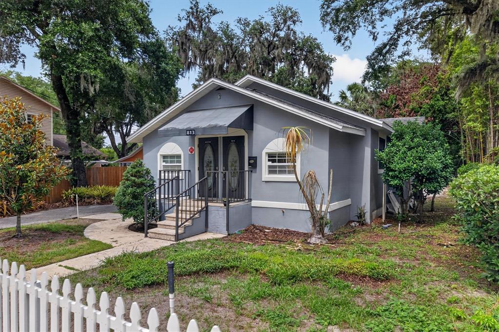 A gray, single-story house with a front porch, metal awning, and white picket fence — 813 N FERN CREEK AVENUE, ORLANDO, FL