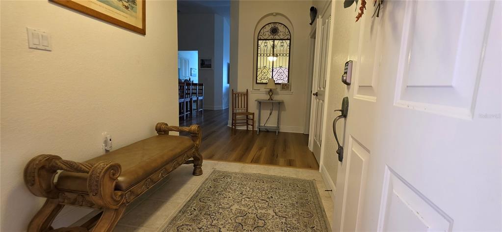 An entryway features a wooden bench, a patterned rug, and a view into the home — 222 LEWIS CIRCLE UNIT 142, PUNTA GORDA, FL
