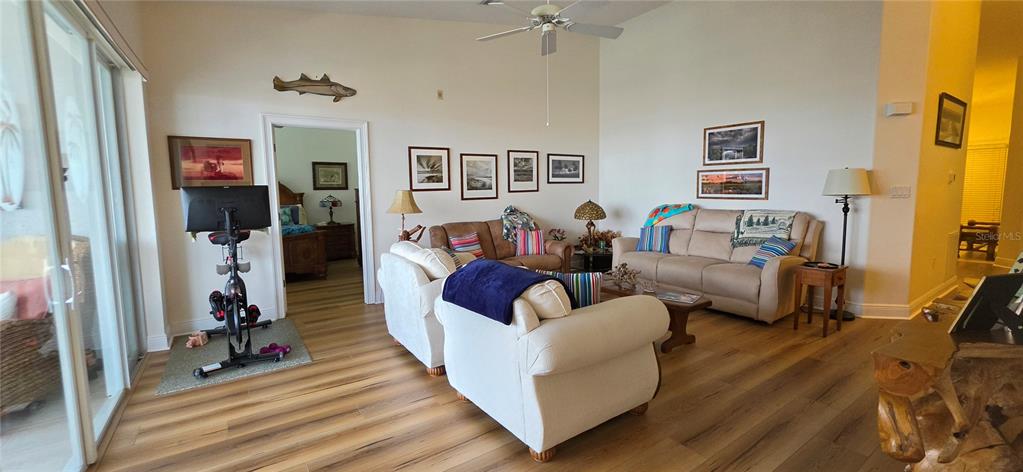 A living room features light wood flooring, a ceiling fan, and two beige sofas — 222 LEWIS CIRCLE UNIT 142, PUNTA GORDA, FL