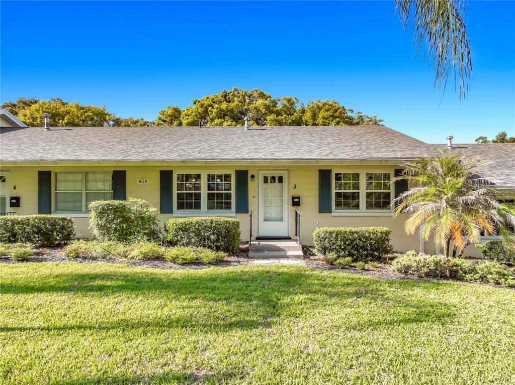 A single-story yellow house with dark shutters, a white front door, and a grassy lawn — 450 LIBERTY AVENUE UNIT 3, MOUNT DORA, FL