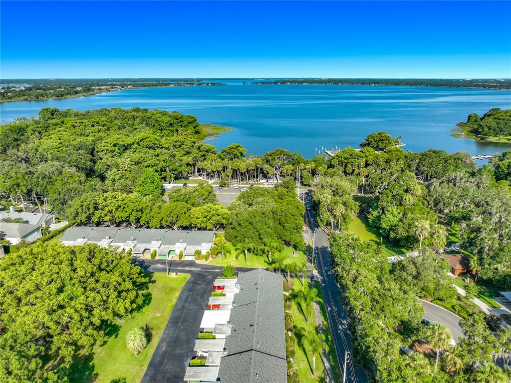 An aerial view shows a residential building complex situated near a large lake and trees — 450 LIBERTY AVENUE UNIT 3, MOUNT DORA, FL